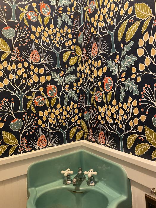 Dark botanical powder room with a vintage green sink