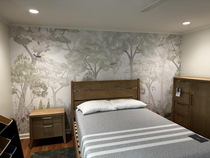 Soft woodland mural behind a bed