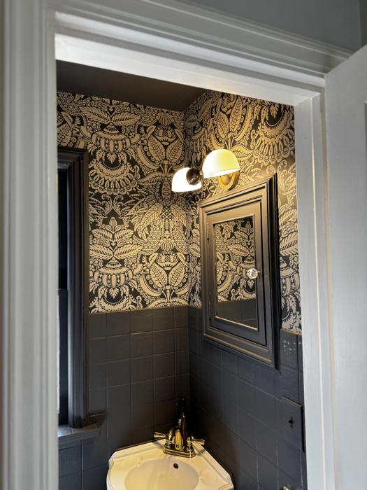 Damask powder room with a gold sconce