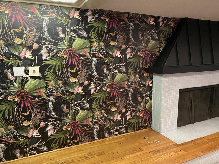 Tropical jungle print beside a black fireplace