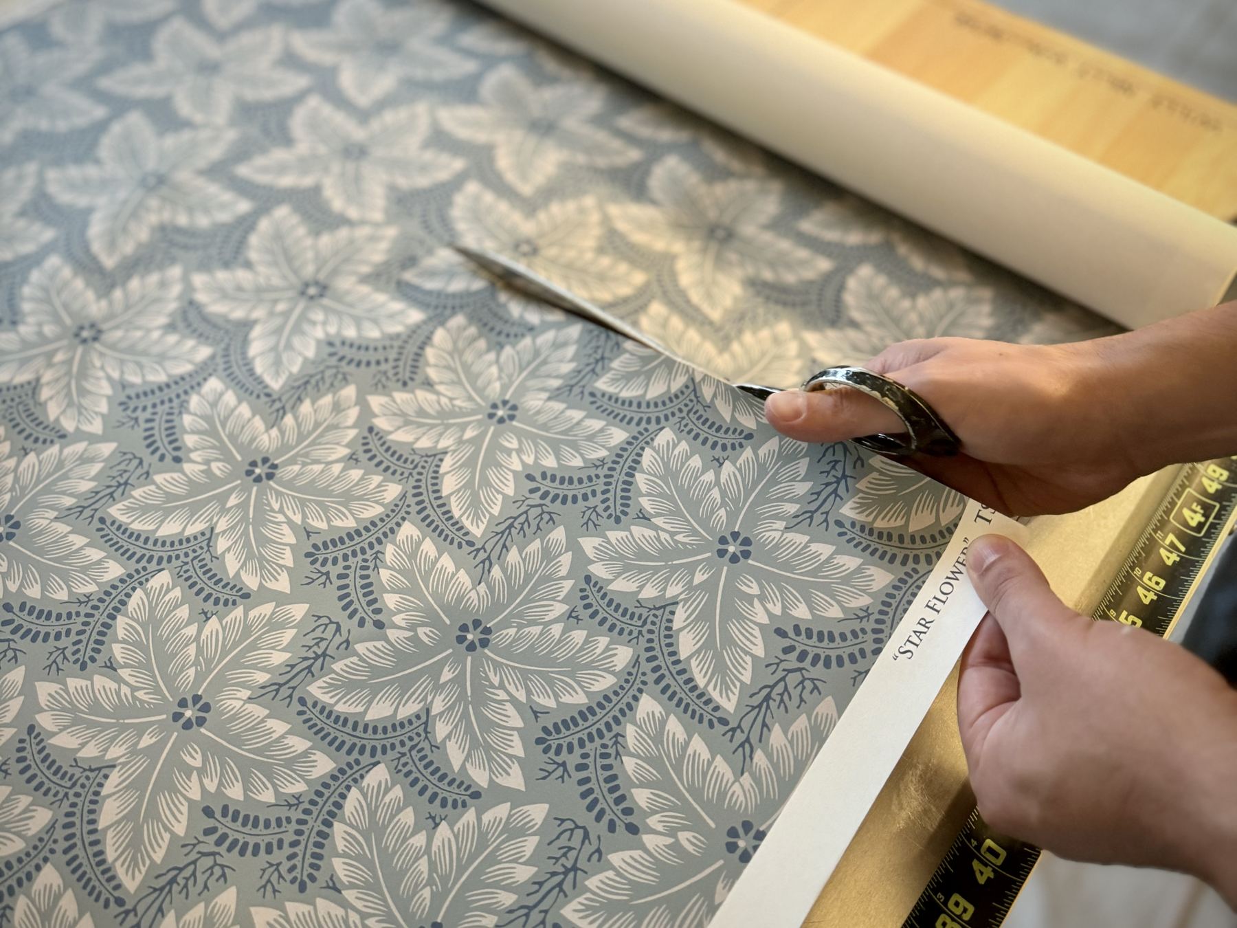 Cutting a blue floral wallpaper with scissors